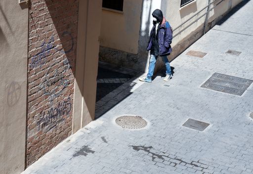Man wearing sanitary protective mask walking in deserted abandoned small street downtown european town during coronavirus pandemic quarantine