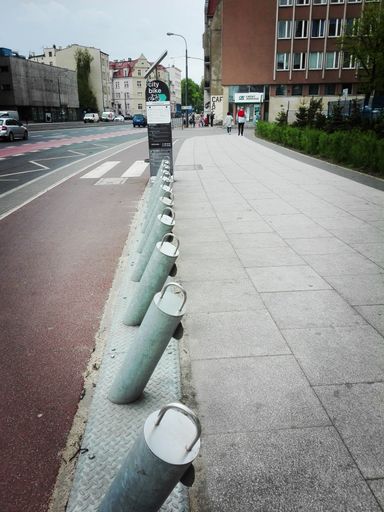 A row of metal poles by a sidewalk of bike rental station in the city center, Poznan, Poland