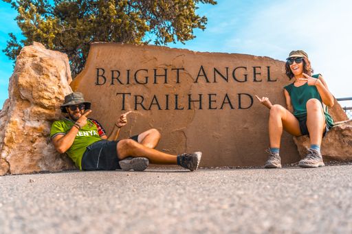 The two happy young tourists pointing to the carved stone in Bright Angel Trailhead Grand, USA