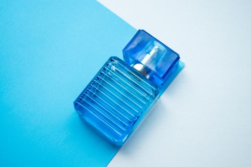 A closeup of a blue perfume bottle on a blue and white background