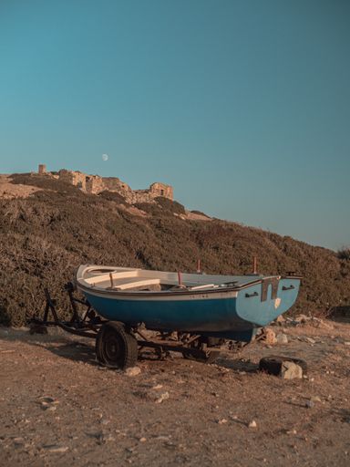 A vertical shot of a blue boat on a barrow in the seashore