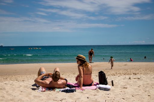 Close up. Young couple sun bathing in Australian beach. Byron Bay, New South Wales.