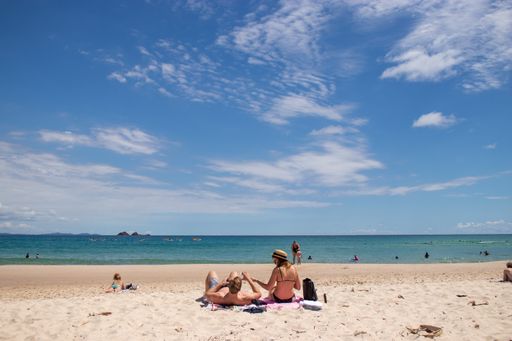 Young couple sun bathing in Australian beach. Byron Bay, New South Wales.