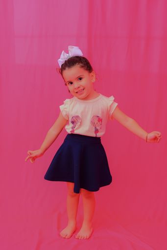 A cute happy small Argentinean girl standing on pink background