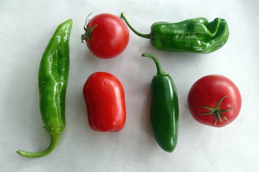 The fresh green peppers and tomatoes on white background