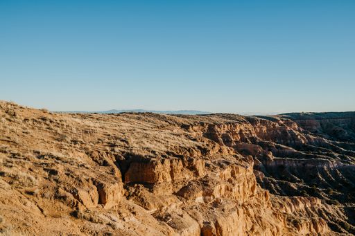 A scenic view of a desert canyon under a clear blue sky, showcasing rugged terrain and natural beauty.