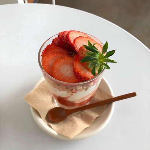 A vertical shot of a strawberry smoothie with a spoon and a saucer