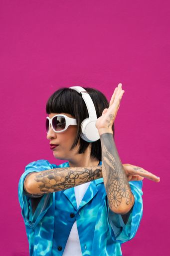 A sexy young woman with tatted arms from Spain in a vibrant blue shirt posing in a studio