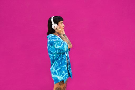 A side-view of an attractive young woman from Spain with tattooed arms listening to music