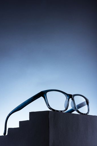 A vertical shot of glasses on a stand isolated on a blue background