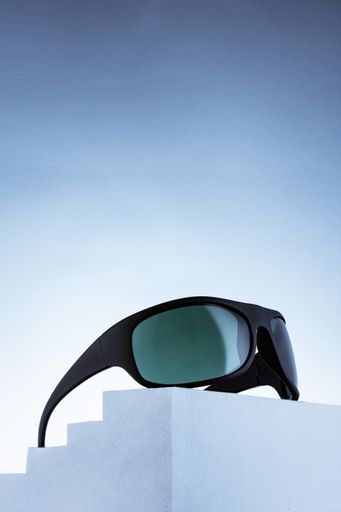 A vertical shot of cycling sunglasses on a stand isolated on a blue background