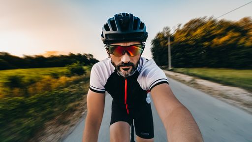 A closeup shot of a bicycle rider on the road making a selfie during the riding