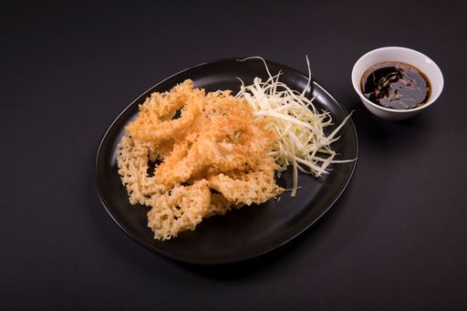 A top view of fried shrimps served with cheese and soy sauce on a black background
