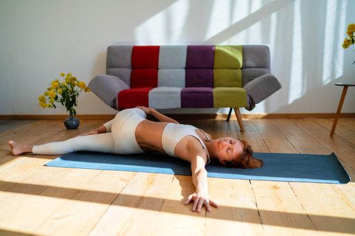 A closeup shot of a Caucasian woman with white sports wear doing yoga, in the room in Ukraine