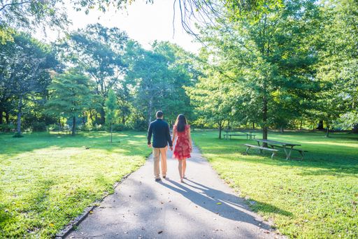 A happy couple walking down a path in a gorgeous green park on a sunny day
