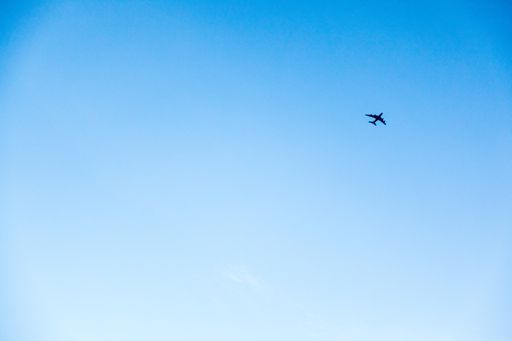 A shot of a plane flying in the bright blue sky
