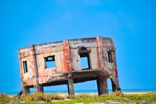 A selective focus shot of building ruins in a field on the seaside