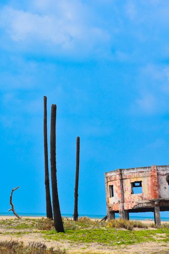 A vertical shot of building ruins in a field on the seaside
