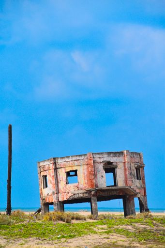 A vertical shot of building ruins in a field on the seaside