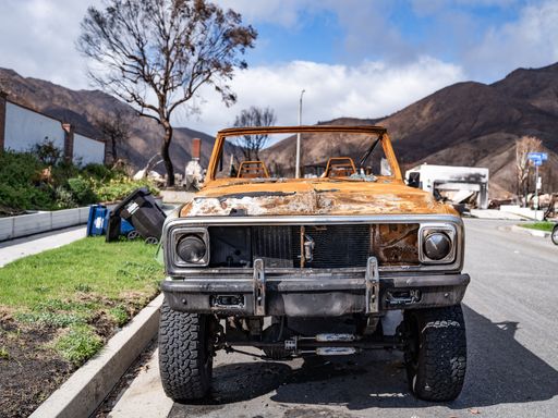 A rusted vintage car parked outdoors in a natural setting