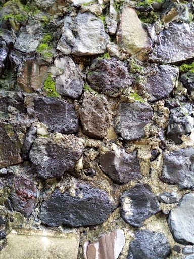 A vertical shot of stoned wall with moss in some places