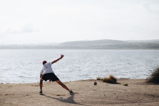 A male doing yoga at a beach during the daytime