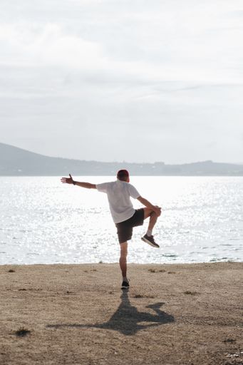 A vertical shot of a male doing yoga at a beach during the daytime
