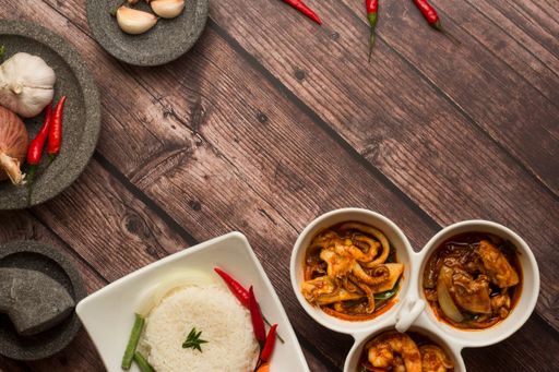 A top shot of rice and shrimps and octopus in sauce served in white three-section condiment ceramic bowls