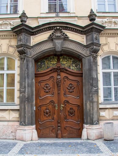 A vertical shot of the doors of a house surrounded by windows