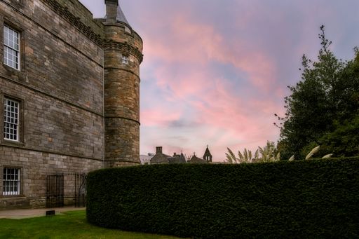 The historic castle wall with lush greenery and a vibrant sunset sky. Edinburgh, Scotland