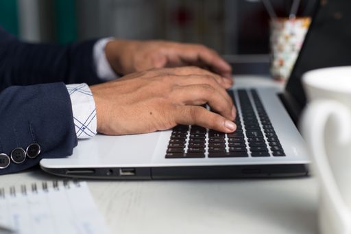 A young man in a suit working on a laptop or studying