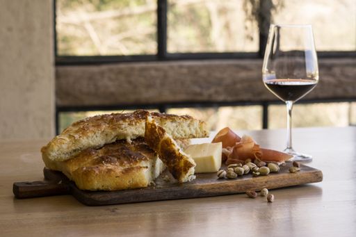A view of a wooden board Focaccia, ham cheese, wine and pistachio