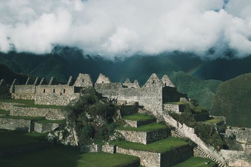 A breathtaking view of Machu Picchu with green terraces and a towering mountain under a cloudy sky