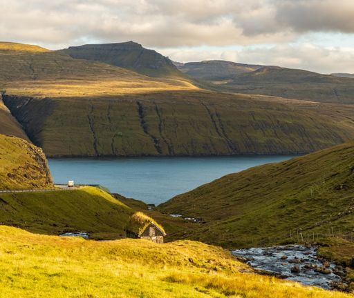 A high angle shot of a beautiful lake surrounded by green mountains under a cloudy sky