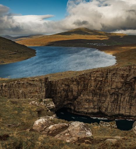 A beautiful scenery of rocky cliffs by the sea in the Faroe Islands under a cloudy sky