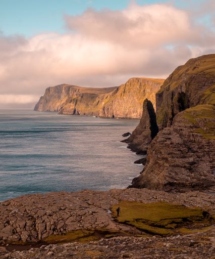 A beautiful scenery of rocky cliffs by the sea in the Faroe Islands under a cloudy sky