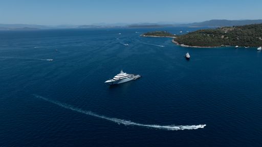 Aerial view of luxury yachts cruising in the Aegean Sea near Bodrum, Turkey, on a clear sunny day with islands in the background.