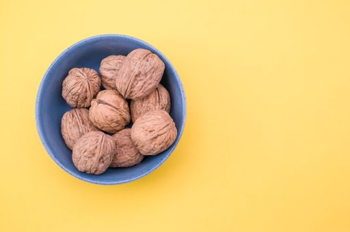 Top view shot of whole walnuts in a  bowl isolated on a yellow background