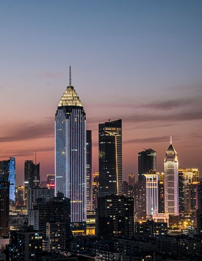 A scenic view of skyscrapers on Wuhan Financial Street illuminated by neon lights at sunset