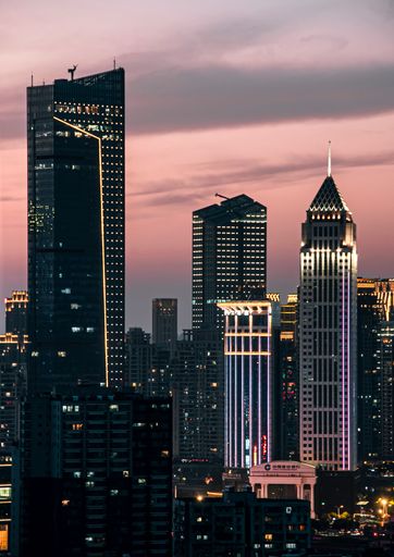 A scenic view of skyscrapers on Wuhan Financial Street illuminated by neon lights at sunset
