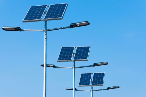 Solar-powered street lights with panels against a clear blue sky, showcasing renewable energy technology.