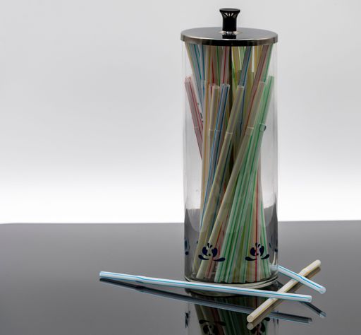 A transparent cylindrical container holds various colorful plastic straws, neatly arranged and visible.