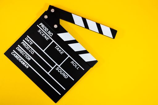 Film clapperboard on a vibrant yellow background symbolizing filmmaking and creativity.