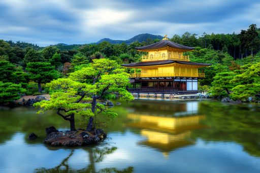 Scenic view of Kinkaku-ji, the Golden Pavilion, reflecting in a tranquil pond surrounded by lush greenery in Kyoto, Japan.