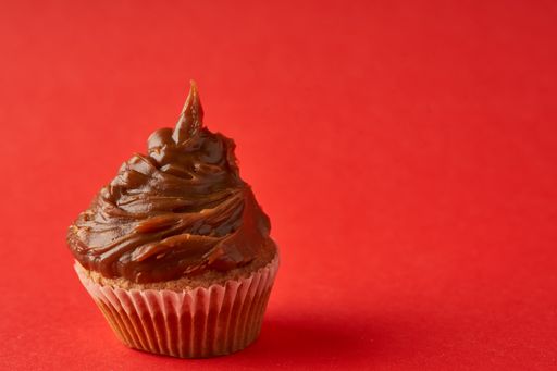 A closeup of a cupcake with dulce de leche against a red background