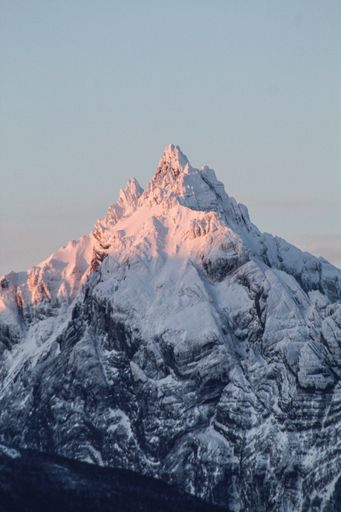 A vertical shot of a volcano mountain peak covered by snow  under sunlight