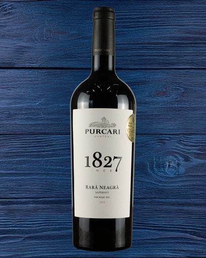 Bottle of Purcari 1827 Rara Neagra red wine on a dark blue wooden surface