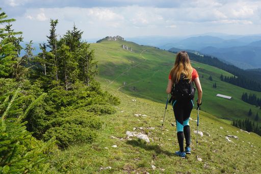 A beautiful shot of a female hiker hiking in the mountain under the blue sky in summer