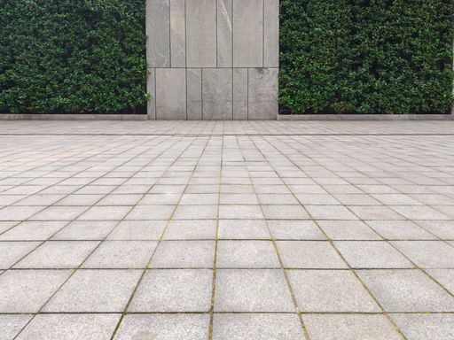 A building's yard with a green wall and concrete floor