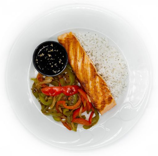A top shot of a white decorative plate with rice, fried peppers, and grilled salmon with sauce